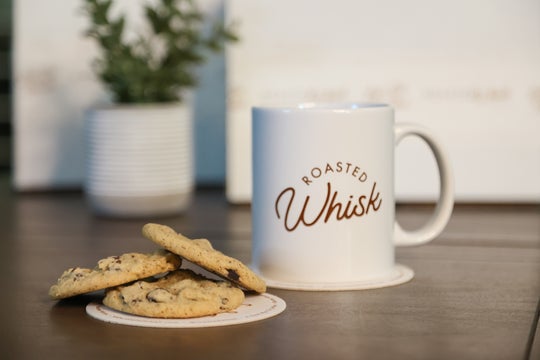 Coffee mug with cookies on wooden table.